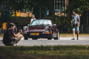 a man sitting on the ground next to a car